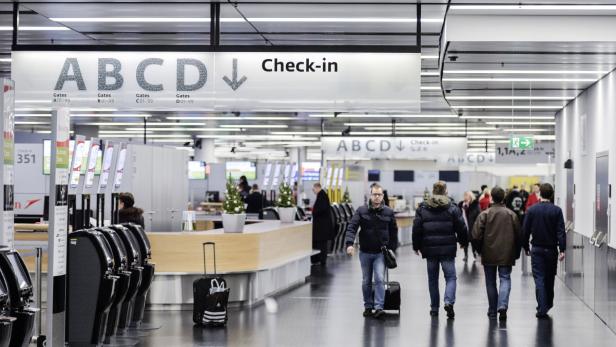 Flughafen-Check-in-Bereich mit Menschen und Gepäckwagen.