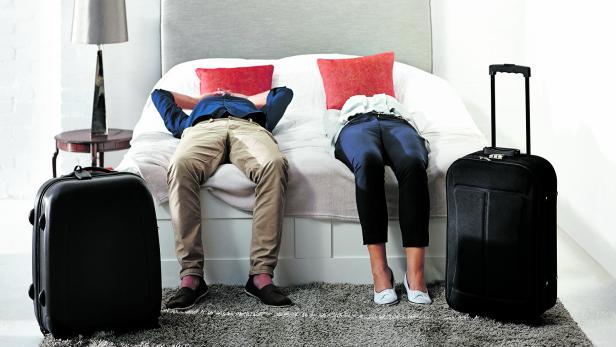 Mature couple lying on bed with luggage