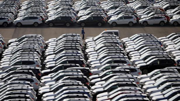 FILE PHOTO: A worker is seen among newly manufactured cars awaiting export at port in Yokohama