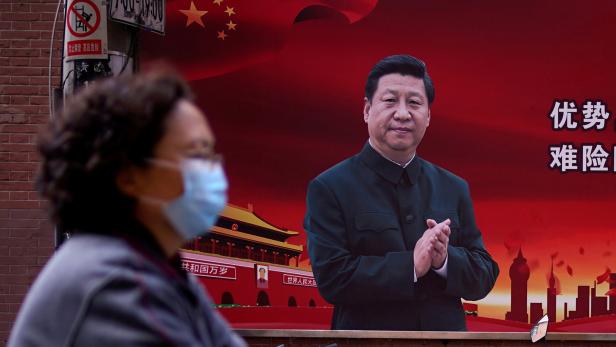 Shanghai: Eine Frau mit Schutzmaske vor einem Porträt von Präsident Xi Jinping