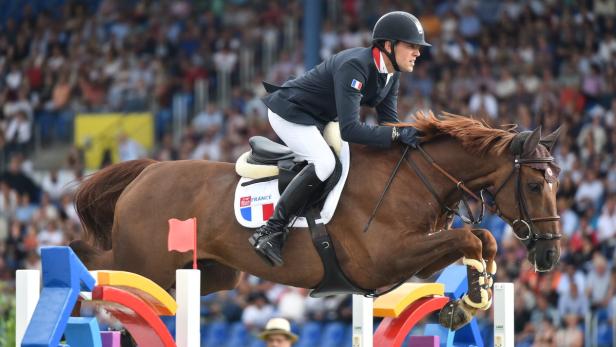 Ein französischer Reiter springt mit seinem Pferd über ein Hindernis.