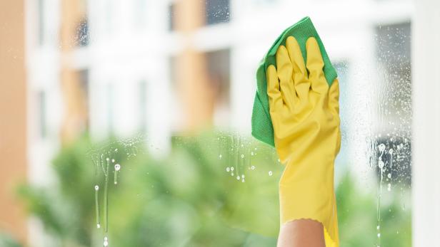 Woman housekeeper cleaning the mirror with green cloth