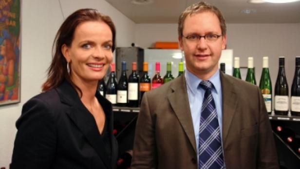 Andi Huggel und Esther Roth posieren vor einem Regal mit Weinflaschen.