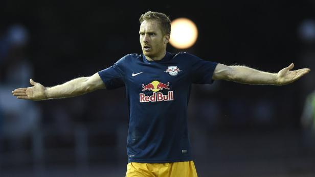 Ein Fußballspieler mit rotem Haar und einem Trikot von Red Bull streckt die Arme aus.