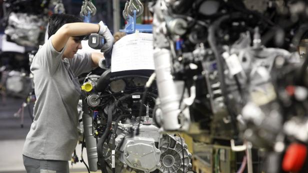 Eine Arbeiterin montiert einen Motor in einer Fabrikhalle.