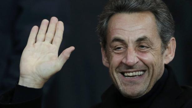 Nicolas Sarkozy lächelt und winkt in die Kamera.