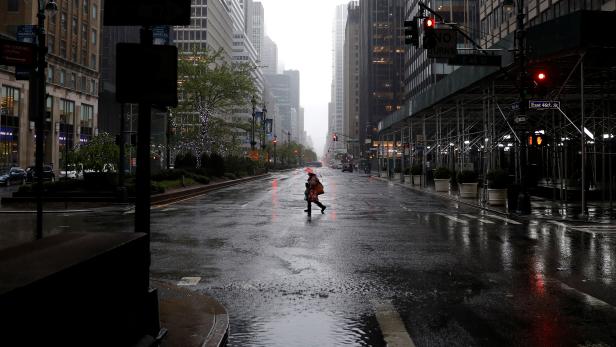 Man walks in heavy rain and high winds across nearly empty Park Avenue during outbreak of coronavirus disease (COVID-19) in New York