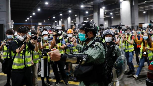 A riot police holds a pepper spray as he tries to disperse anti-government protesters after a vigil to mourn students death, in Hong Kong