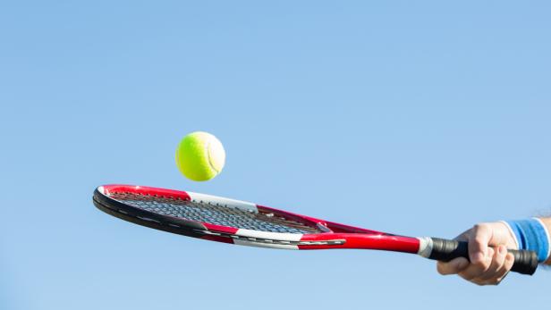 Ein Tennis-Ball auf einem Schläger.