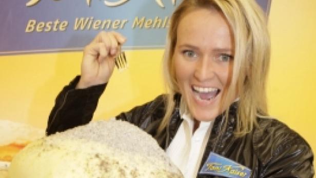 Eine Frau präsentiert strahlend einen großen Germknödel von Toni Kaiser.