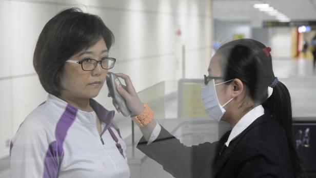 An airport staff member wearing a mask takes a passenger&#039;s temperature at Taoyuan International Airport, northern Taiwan, April 24, 2013. A 53-year-old Taiwan businessman has contracted the H7N9 strain of bird flu while travelling in China, Taiwan&#039;s Health Department said on Wednesday, the first reported case outside of mainland China. REUTERS/Stringer (TAIWAN - Tags: HEALTH ENVIRONMENT) TAIWAN OUT. NO COMMERCIAL OR EDITORIAL SALES IN TAIWAN