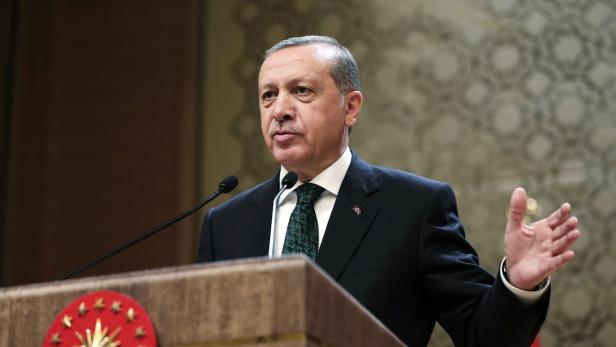 Recep Tayyip Erdoğan hält eine Rede vor einem verzierten Hintergrund.