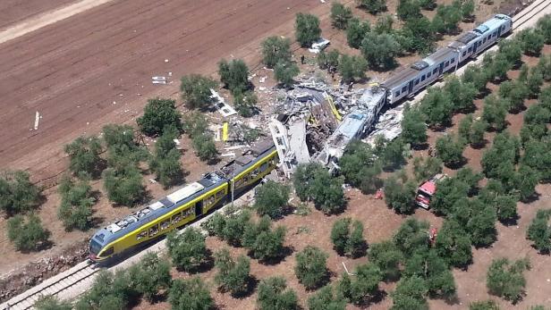 Ein schwerer Zugunfall zwischen Olivenbäumen mit Trümmern und Rettungskräften vor Ort.