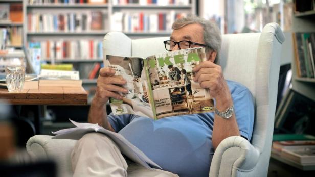 Ein Mann liest in einem Sessel sitzend einen IKEA-Katalog.