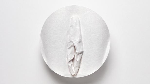 Ein zerknittertes, weißes Papiertuch liegt auf einem weißen Teller.