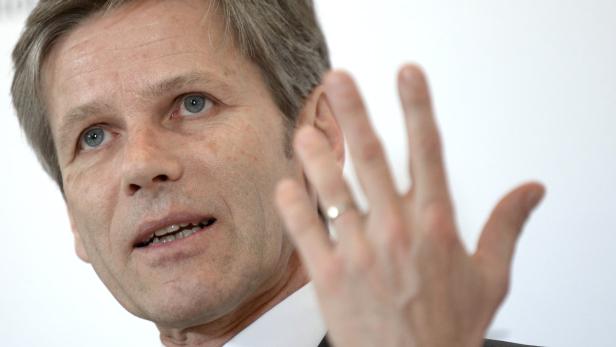 Ein Mann mit grauem Haar gestikuliert mit der Hand.