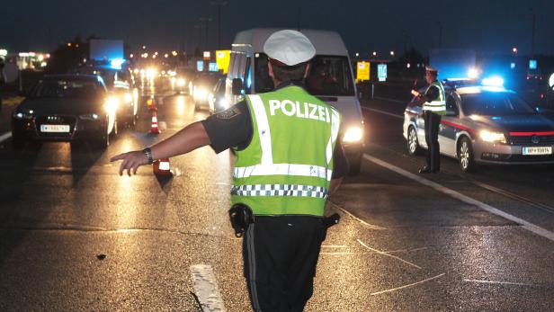 Ein Polizist leitet den Verkehr bei einer nächtlichen Kontrolle auf der Autobahn.