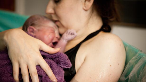 Mother Holding Newborn in Birthing Tub After Home Water Birth