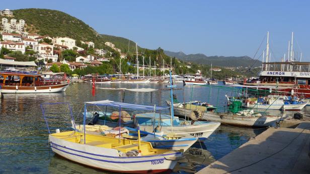 Mehrere Boote liegen in einem Hafen vor einer Küstenstadt.