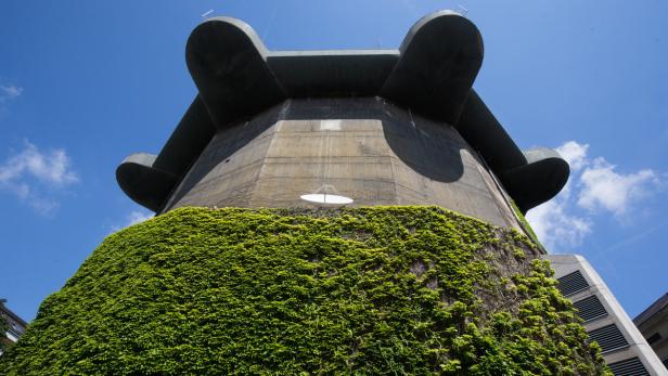 Ein Hochbunker, teilweise mit Efeu bewachsen, unter blauem Himmel.
