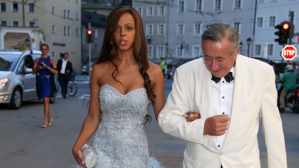 Eine elegant gekleidete Frau und ein Mann im Smoking überqueren eine Straße.