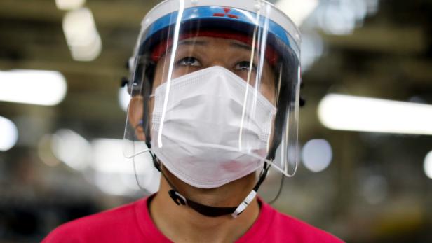An employee wearing a protective face mask and face guard works on the automobile assembly line during the outbreak of the coronavirus disease (COVID-19) at the factory of Mitsubishi Fuso Truck and Bus Corp. in Kawasaki
