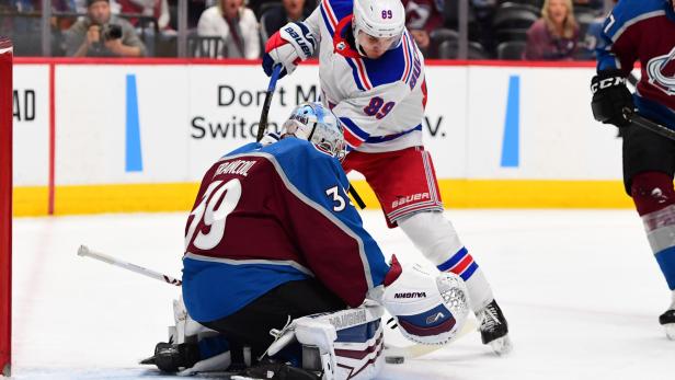 Ein Hockeyspieler versucht, den Puck am Torwart vorbeizuschießen.