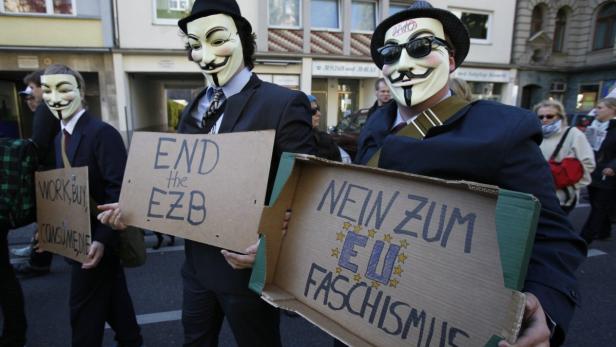 Protesters of Cologne&#039;s &#039;Anonymous&#039; group wear Guy Fawkes masks made popular by the graphic novel &quot;V for Vendetta&quot; as they demonstrate against banking and finance in Cologne October 15, 2011. Protesters worldwide geared up for a cry of rage on Saturday against bankers, financiers and politicians they accuse of ruining global economies and condemning millions to poverty and hardship through greed. The placards read L-R &#039;Work, Buy, consume - No&#039;, &#039;End the European Centrab Bank ECB&#039; and &#039; No EU fascism&#039;. REUTERS/Wolfgang Rattay (GERMANY - Tags: BUSINESS POLITICS CIVIL UNREST)