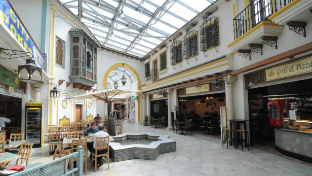 Ein Innenhof mit Restaurants und einem Brunnen unter einem Glasdach.