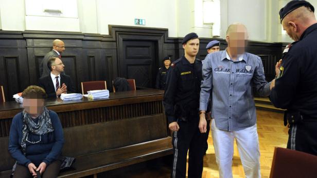 Ein Mann wird im Gerichtssaal von Justizbeamten in Handschellen abgeführt.