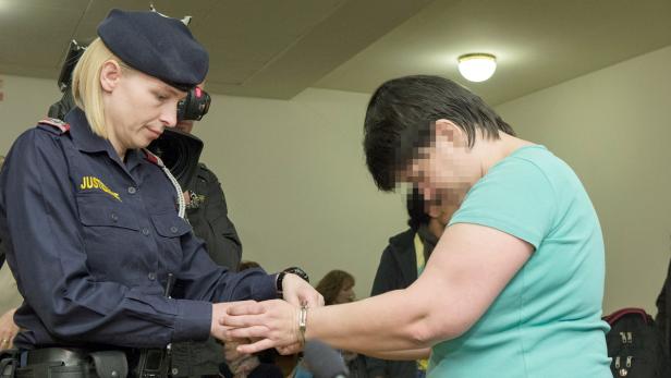 Eine Justizbeamtin legt einer Frau Handschellen an.