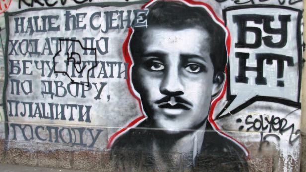Ein Graffito zeigt ein Porträt mit kyrillischer Schrift im Hintergrund.