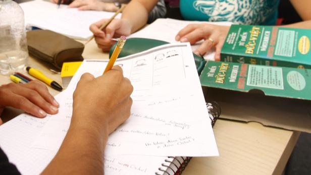 Mehrere Personen sitzen an einem Tisch und lernen Deutsch mit Hilfe von Lehrbüchern.