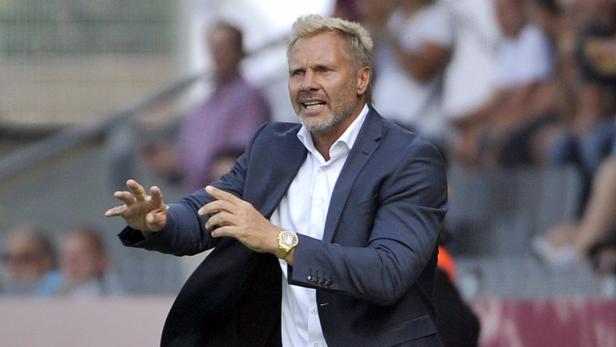 Ein Trainer gestikuliert während eines Spiels an der Seitenlinie.