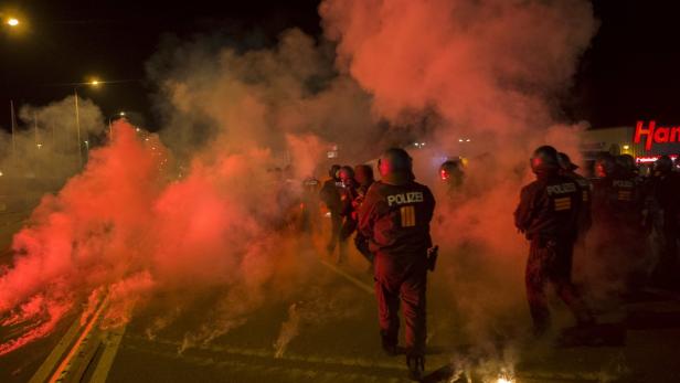 Polizisten stehen inmitten von rotem Rauch auf einer Straße.