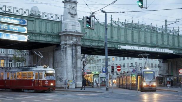 Zwei Straßenbahnen fahren unter der Währinger Straße in Wien durch.