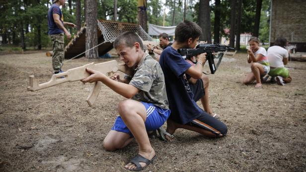 Kinder spielen im Freien mit Spielzeugwaffen.