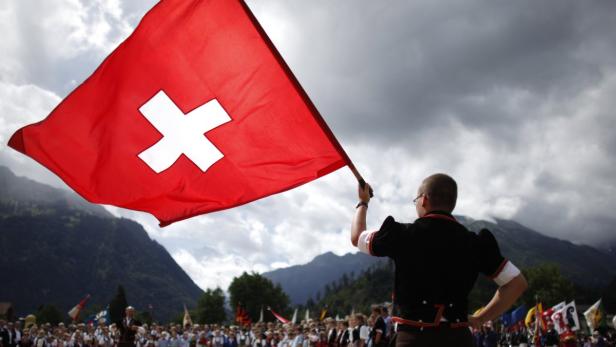 File photo of a boy dressed in traditional a costume waving a Swiss national flag during the official ceremonial act at the 28th Federal Yodelling Festival in Interlaken June 19, 2011. The Swiss economy grew faster than expected in the third quarter after government spending rose even as sluggish exports helped the central bank&#039;s policy of capping the safe-haven franc. Gross domestic product rose 0.6 percent in the third quarter from the previous quarter, compared with a forecast for 0.2 percent and after a 0.1 percent contraction in the second quarter. Year-on-year, gross domestic product rose 1.4 percent, compared with a forecast for 0.9 percent, up from a revised 0.3 percent growth in the previous three months, the State Secretariat for Economics said November 29, 2012. REUTERS/Pascal Lauener/Files (SWITZERLAND - Tags: BUSINESS)