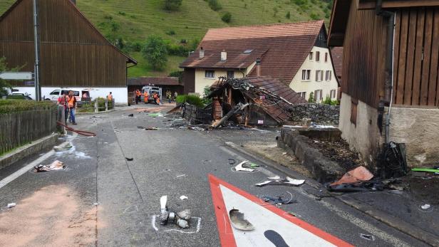 Ein zerstörtes Gebäude liegt an einer Straße, während Rettungskräfte vor Ort sind.
