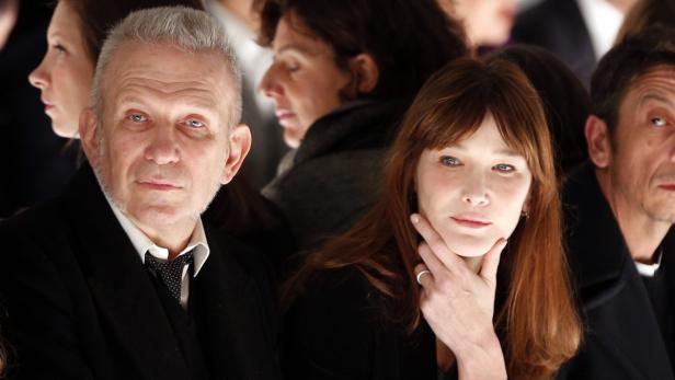 Jean-Paul Gaultier und Carla Bruni sitzen in der ersten Reihe einer Modenschau.