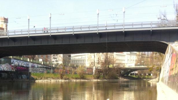 Eine Brücke überspannt einen Fluss in einer städtischen Umgebung.