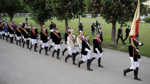 Eine Gruppe von Männern in historischen Uniformen marschiert eine Straße entlang.
