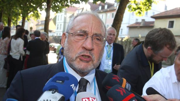 Ein Mann mit Brille spricht in mehrere Mikrofone.