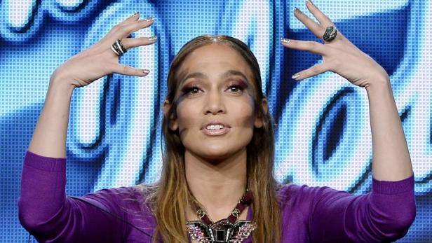 Jennifer Lopez posiert mit erhobenen Händen und auffälligen Ringen.