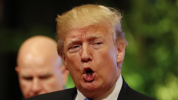 Donald Trump steht mit offenem Mund im schwarzen Sakko und blauer Krawatte vor der Kamera.