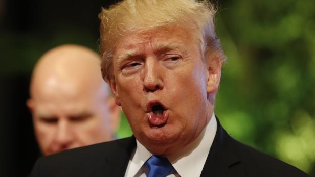 Donald Trump steht mit offenem Mund im schwarzen Sakko und blauer Krawatte vor der Kamera.