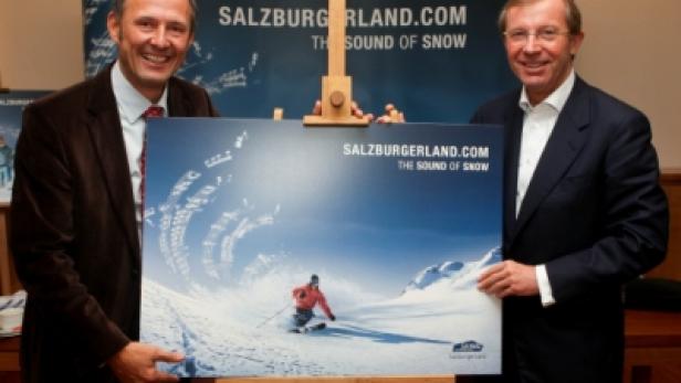 Zwei Männer präsentieren ein Werbeplakat für Salzburgerland.com mit einem Skifahrer.