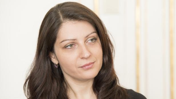 Eine Frau mit langen, braunen Haaren schaut nach rechts.