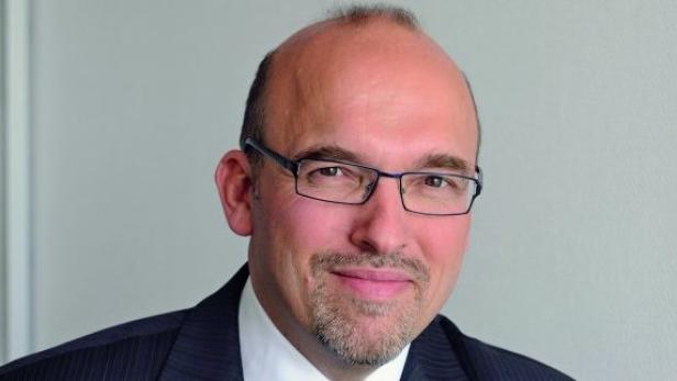 Porträt eines Mannes mit Brille und Anzug.