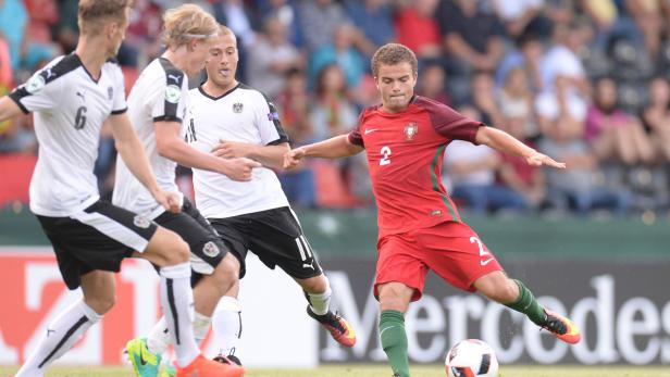 Ein portugiesischer Fußballspieler schießt den Ball, umgeben von österreichischen Gegenspielern.
